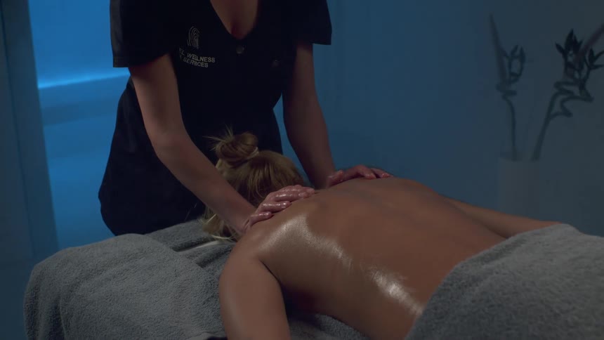Close up of a female massage therapist massaging a female clients back in a spa