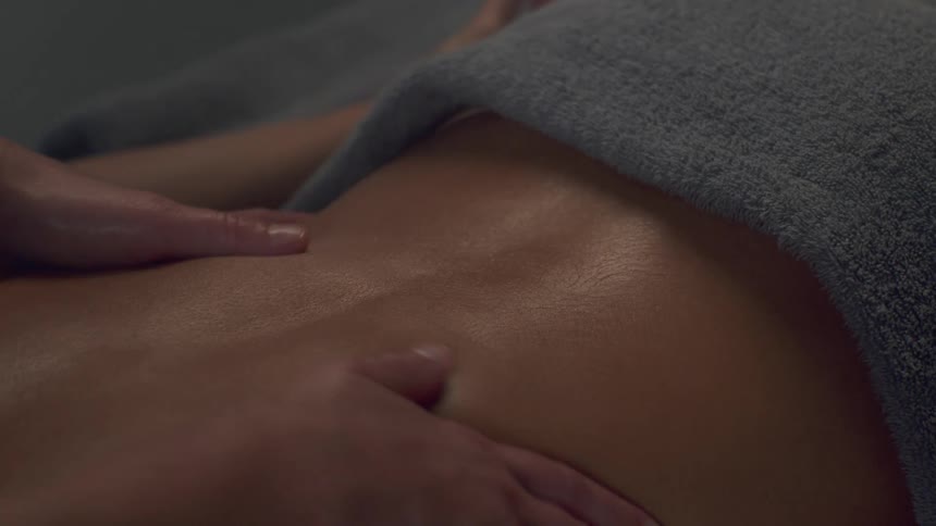 Massage therapist massagesthe well oiled bare skin of a client