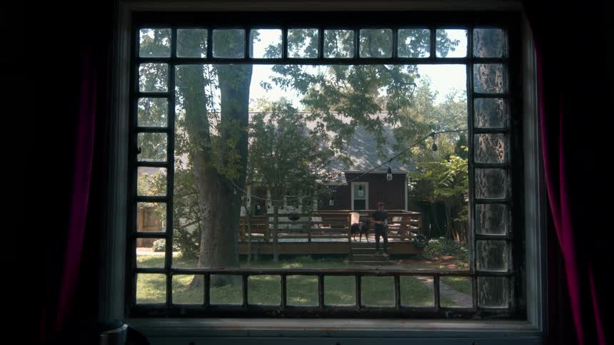 A man walks down the steps of his porch with his dog