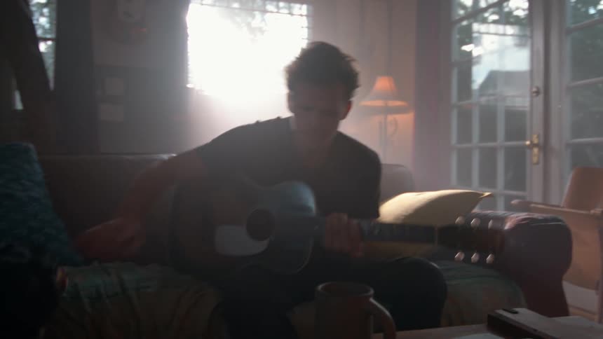 Man sitting and playing guitar next to a dog
