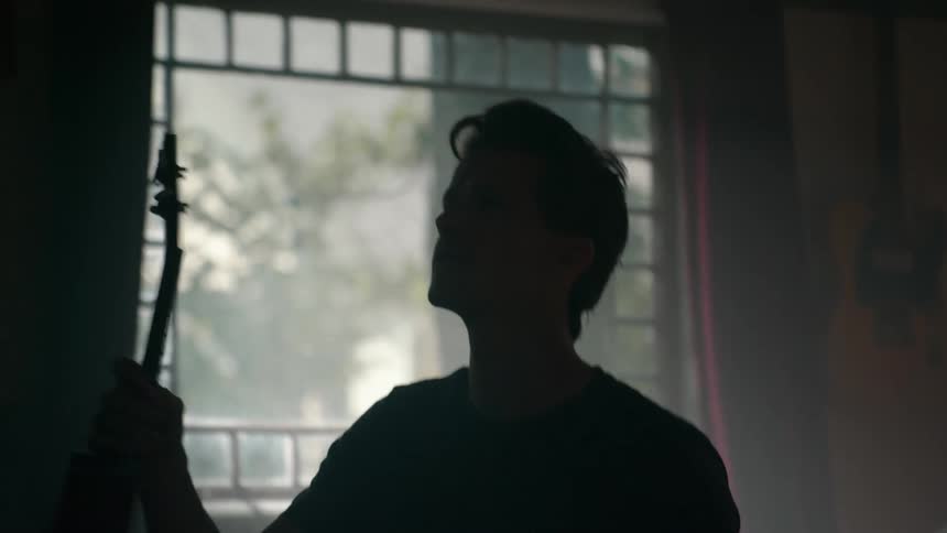 Man storing a guitar in a room of the house