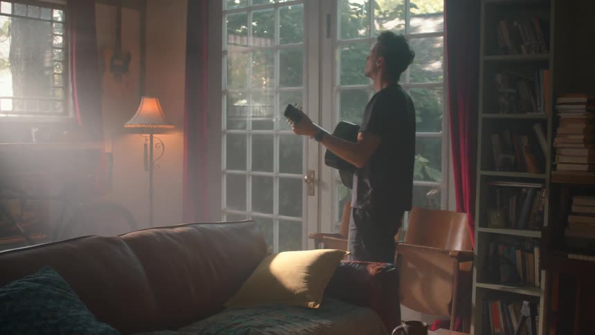 A man is playing the guitar at home