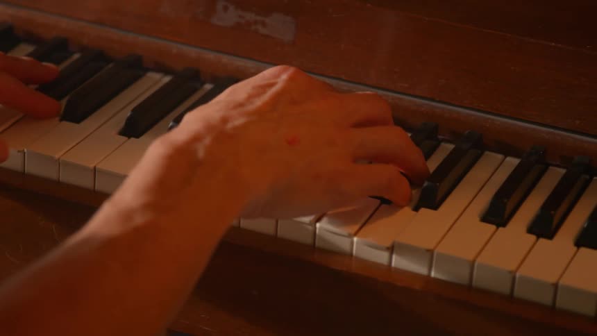 A persons hands playing on a piano with black and white keys