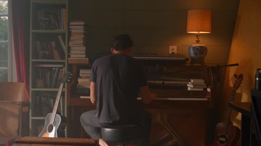 A man plays piano alone in a warmly lit cozy room