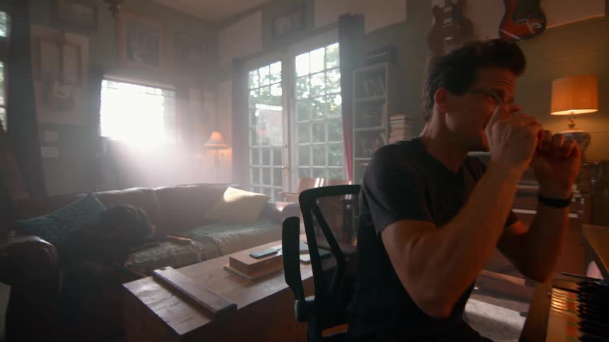 Man sitting in front of a piano and putting on glasses