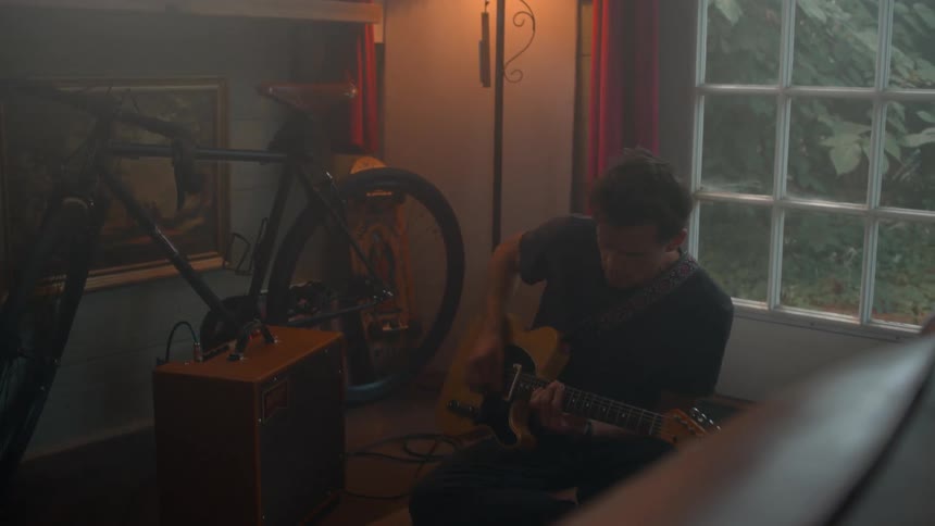 A man in glasses sits focused at a music workstation with a warm ambient background