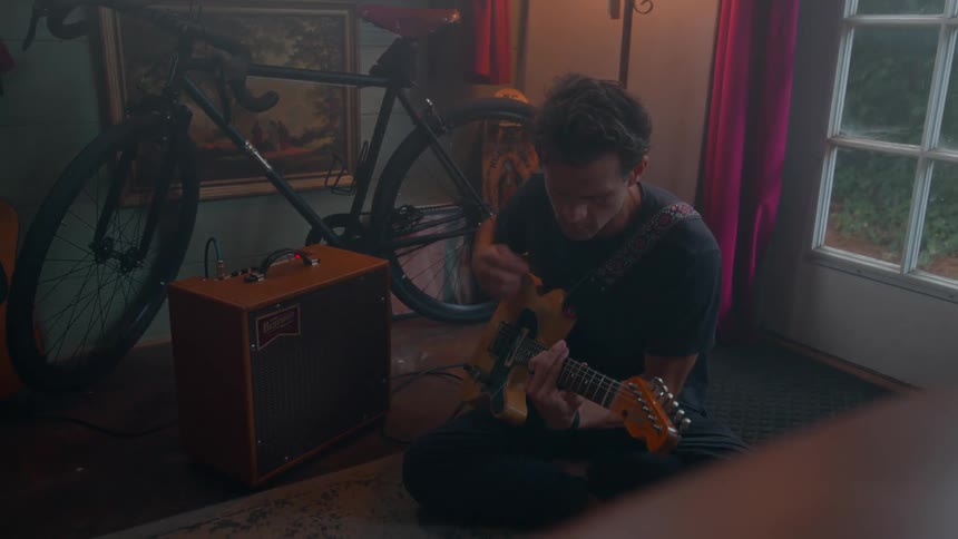 A man sits on the floor and plays guitar
