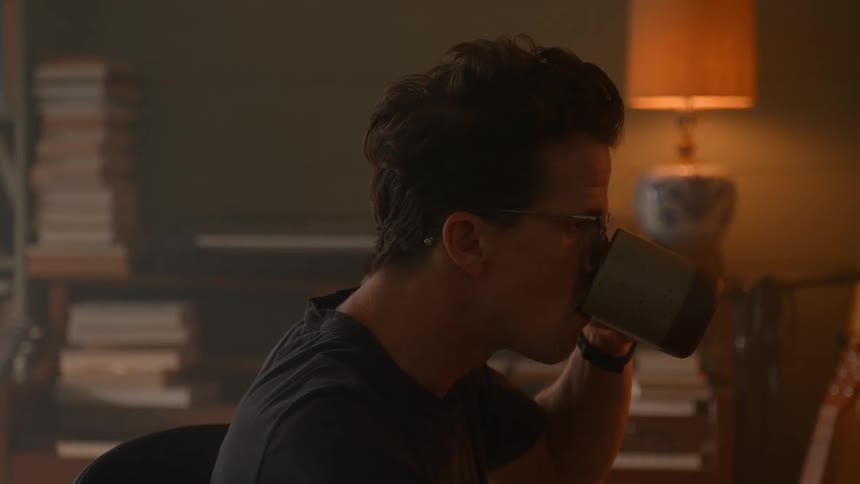 A man is using his computer at home and drinking coffee