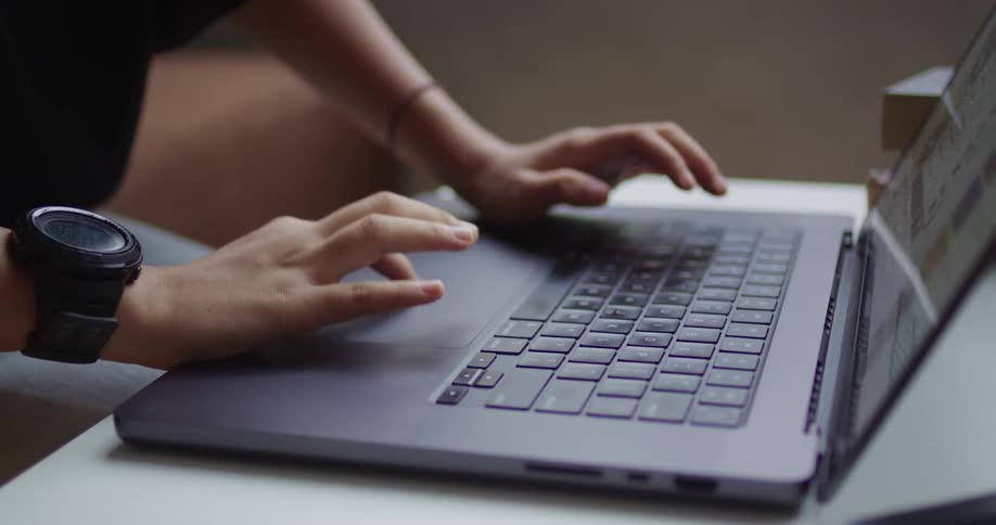 A persons hands typing on a gray laptop keyboard