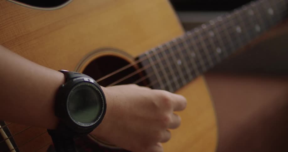 Teen girl strumming an acoustic guitar at home