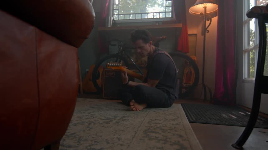 A man sits on the ground and plays guitar