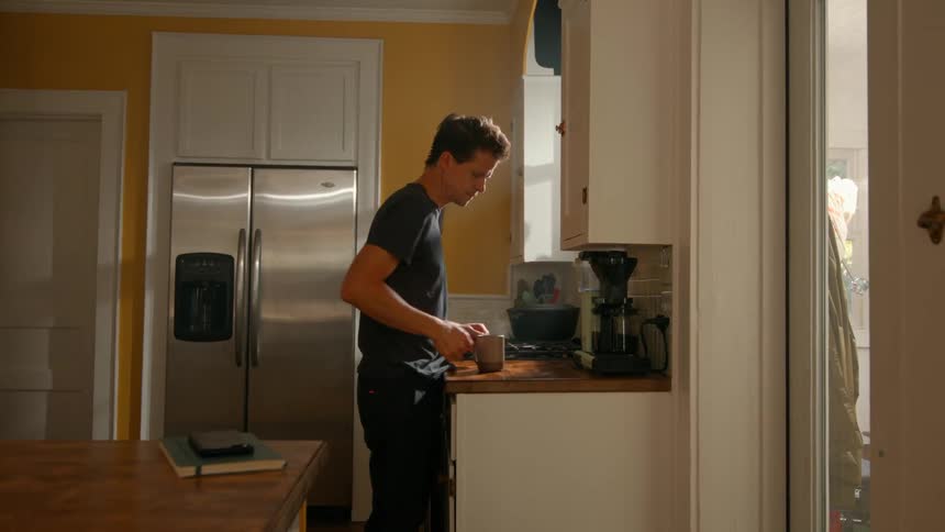 A man pours a cup of coffee in his kitchen