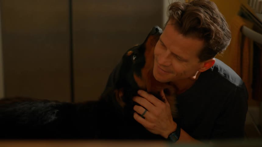 Loving man kissing and petting his dog in his kitchen