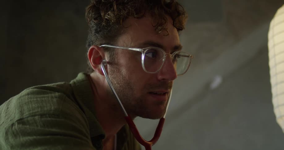 Close up of a young male doctor listening with a stethoscope indoors during daytime