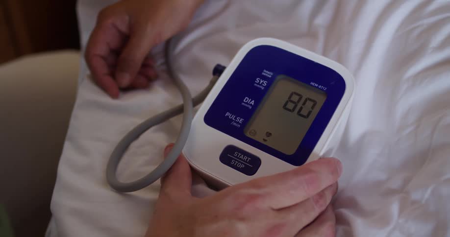 Closeup of a blood pressure gauge on the wrist of a patient in bed