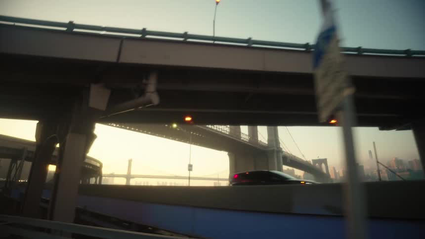 A huge suspension bridge and a highway in front with several cars passing by