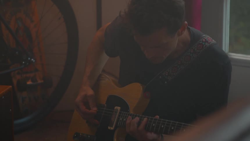 A man plays the electric guitar on the floor