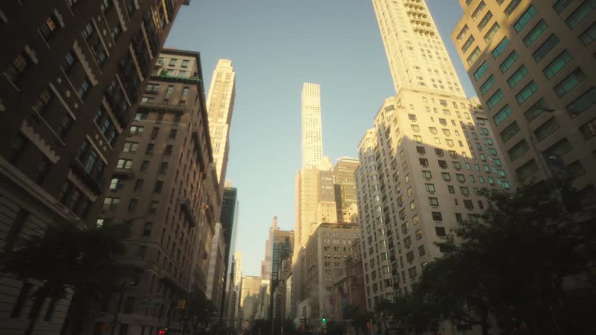 The video shows a lowangle shot looking up at tall buildings with a bright sky in the background the buildings appear modern and are bathed in sunlight suggesting a clear day in an urban environment