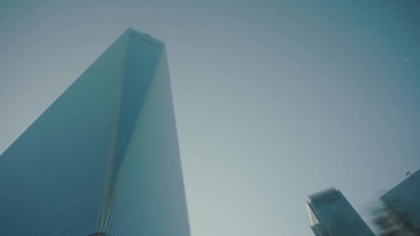 Modern skyscrapers with sleek reflective glass facades stand against a clear blue sky