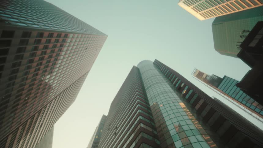Downtown skyscrapers tower over a nearby intersection and reflect nearby buildings