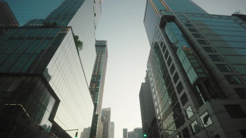 A city skyline view from a street with a series of highrise towers and skyscraper buildings at sunrise