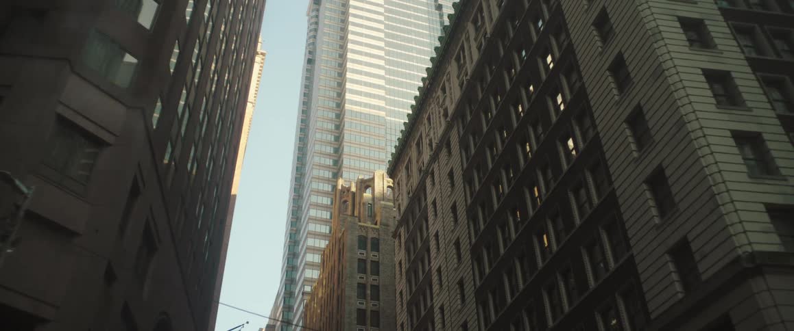 Tall buildings tower over a narrow city street capturing both old and new architectural styles