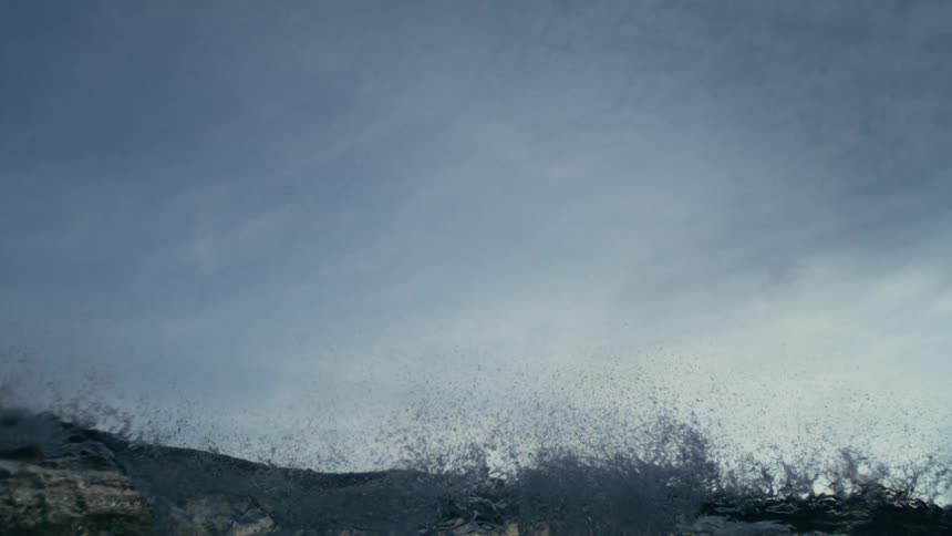 The wave slowly rises under the cloudy sky