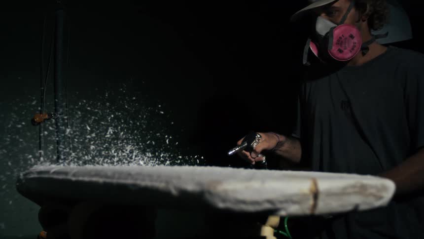 A person wearing a respirator mask cleans a surface in a dusty room