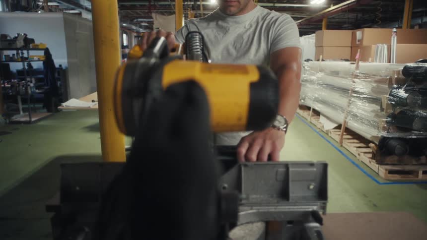 A man operates a hoist machine inside an industrial warehouse