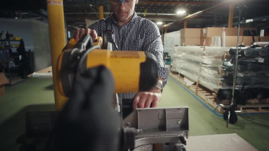 Man in a factory using a manual cutting machine