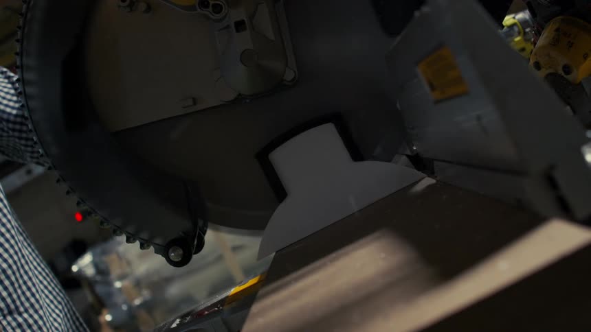 Close up of a young man using an electric circular saw in a factory