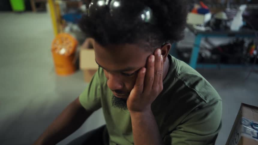 A young black man works with a computer at a desk in a distribution warehouse