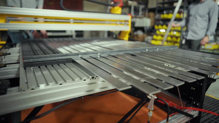 Automated machine in operation with metal profiles aligned on rails in an industrial environment