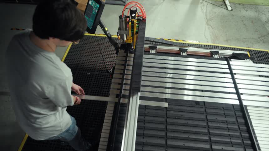 Man in a factory placing metal fillets into an industrial machine