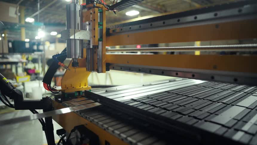 Male worker slides a long flat component into a factory machine