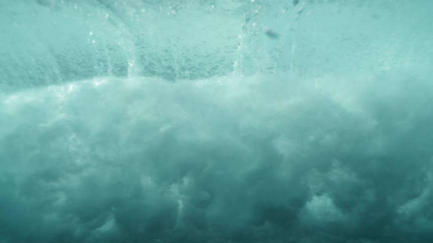 View from just beneath the waters surface captures shimmering reflections above and waves with bubble nearby