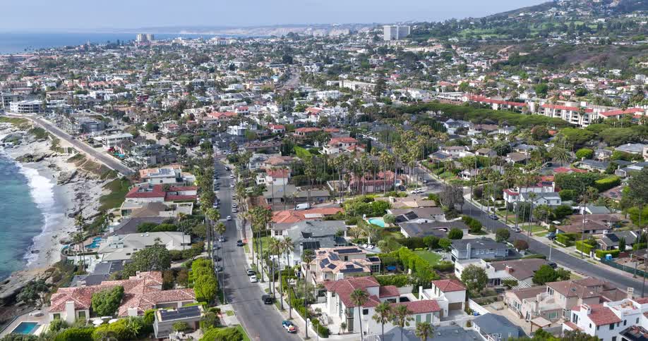 A densely built seaside community with palmlined streets and a mix of residential buildings near the shore