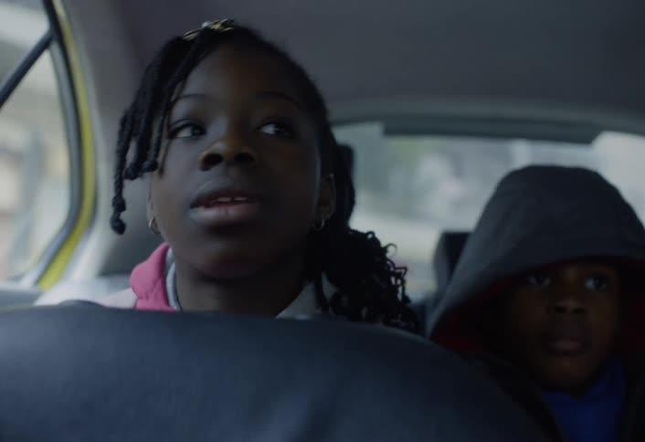 Young teenager talks while sitting in the back of a moving car with her brother