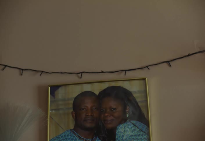 A couple in a picture frame is mounted on a yellowpainted wall with disco lights crossing over the wall