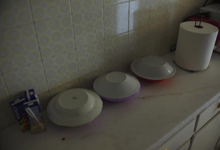Three plates of food each covered with another plate are placed on a countertop in the kitchen