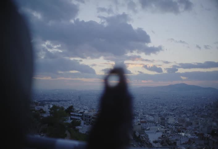 Person with halfclosed hand overlooking an urban city with mountains in the background