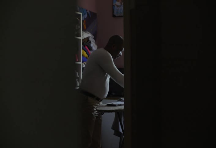 The man is ironing his clothes on an ironing board