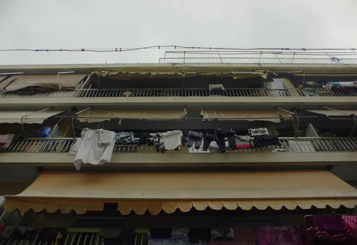 The video shows an apartment building with multiple balconies some of which have clothing hanging out to dry below the balconies there are large scalloped awnings