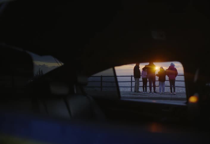 Group of people enjoying the seaside scenery seen through a car window