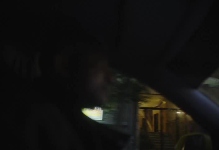 A young man is driving his car through the city at sunset