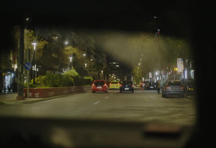 Nighttime traffic flows through a busy city street seen from inside a vehicle