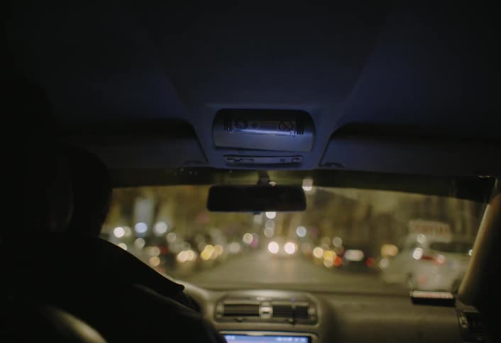 Person driving a car on a city road at night