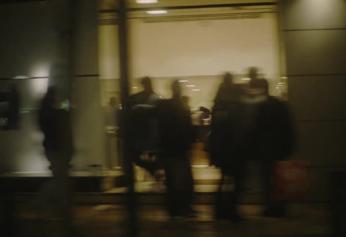 Pedestrians walking on the sidewalk of an urban street in a city at night