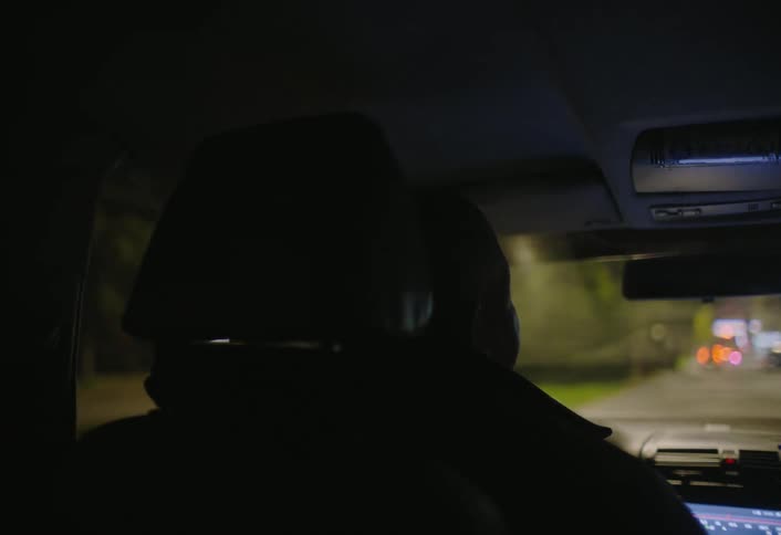 Silhouette of a person driving a car at night