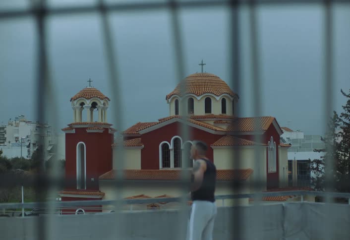 Man in tank top walking outdoors near a church in the background